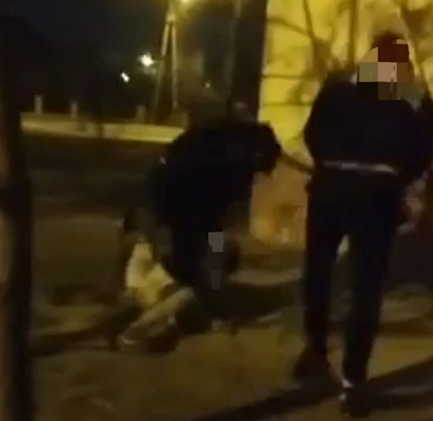 Screenshot from the video. The footage shows the assailants and the boy lying on the ground